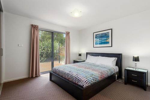 a bedroom with a bed and a large window at 170 Hazards View Drive - Unit 2 in Coles Bay
