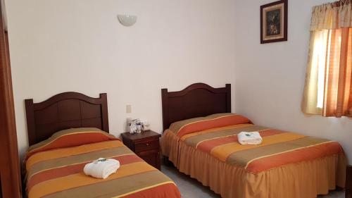 two beds in a hotel room with towels on them at El Jardín Del Edén in Tequisquiapan