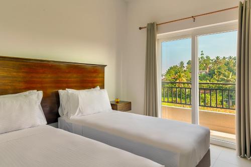 two beds in a hotel room with a window at Fairway Sunset Serviced Apartments in Galle