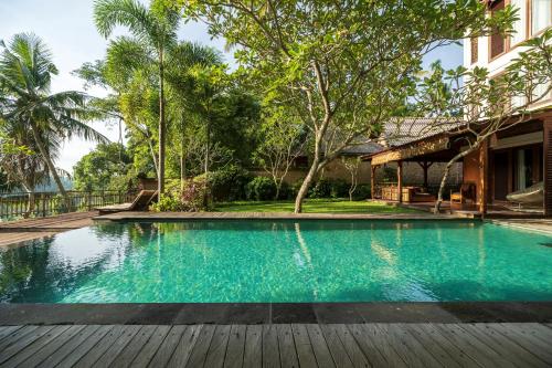 a swimming pool in front of a house at Adiwana Svarga Loka - A Retreat Resort in Ubud