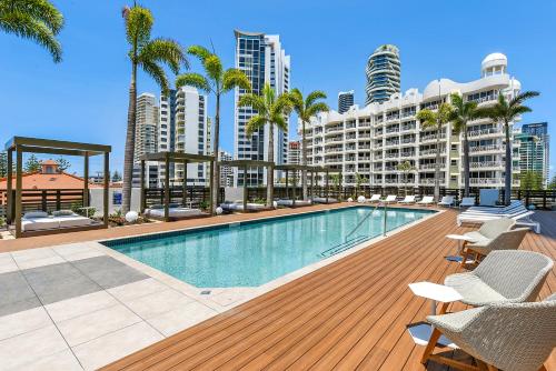 a swimming pool with palm trees and buildings at Qube Broadbeach Ocean View Apartments in Gold Coast