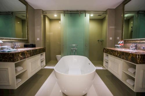 a bathroom with a large tub and two sinks at Hotel Santika Seminyak in Seminyak