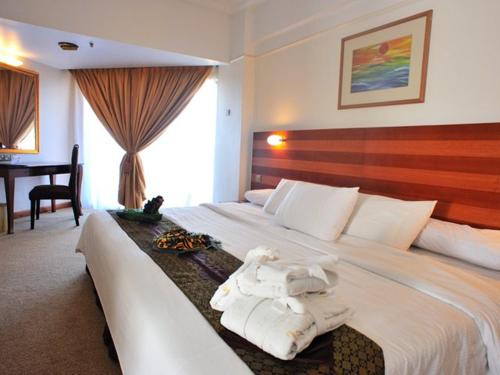 ein Hotelzimmer mit einem großen Bett mit Handtüchern darauf in der Unterkunft Primula Beach Hotel in Kuala Terengganu