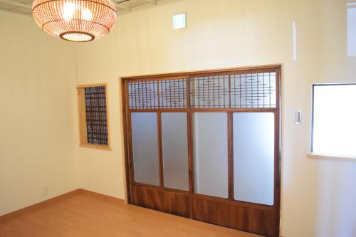 een kamer met een houten deur en een kroonluchter bij MACCHI（マッチ） in Imabari