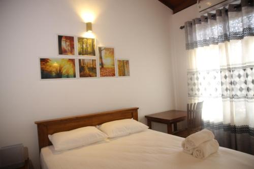 a bedroom with a bed with white sheets and a window at Nimnada Villa in Galle