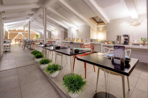 a restaurant with tables and chairs with plants at Best Western Plus Royal Superga Hotel in Cuneo