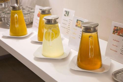 four bottles of orange juice on plates on a table at Best Western Plus Royal Superga Hotel in Cuneo