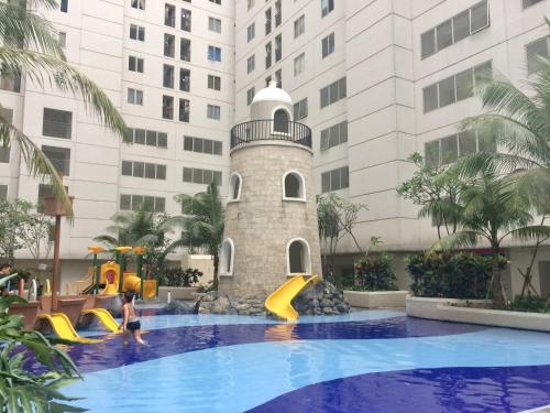 een zwembad met een glijbaan voor een gebouw bij Channel Stay @ Bassura City Apartment in Jakarta