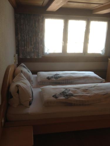 two twin beds in a room with two windows at Café-Conditorei Hotel Huber in Lichtensteig