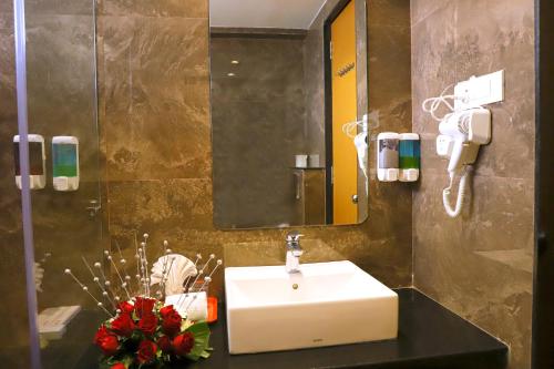 a bathroom with a sink and a mirror at Sai Neem Tree Hotel in Shirdi