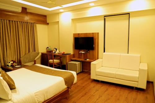 a hotel room with a bed and a chair at Sai Neem Tree Hotel in Shirdi