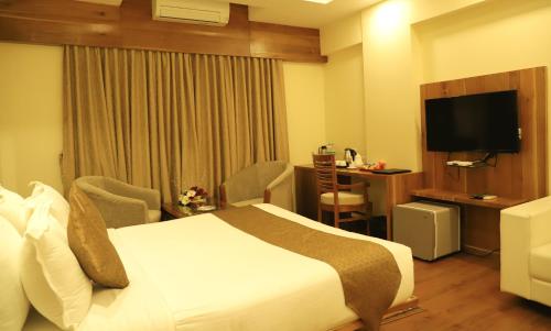 a hotel room with a bed and a television at Sai Neem Tree Hotel in Shirdi