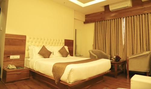 a hotel room with a bed and a chair at Sai Neem Tree Hotel in Shirdi