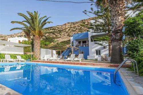 a swimming pool in front of a house with palm trees at Marina Hotel in Matala