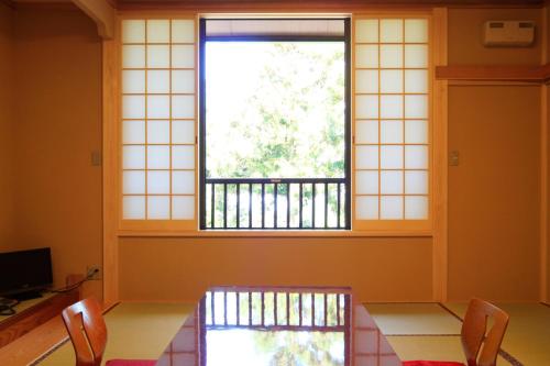 a room with a table and chairs and a window at Nobori in Ome