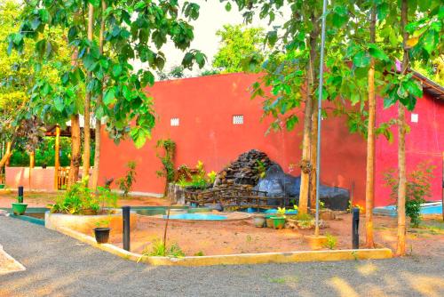 a red building with a fire place in a yard at La Casa Safari Resort in Udawalawe
