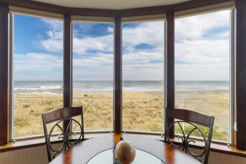 a dining room with a table and chairs and a view of the ocean at Expansive Views Family Oceanfront Beach Home in Westport