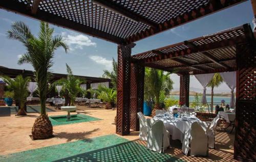a patio with a table with white tables and chairs at Rive Du Lac in Lalla Takerkoust