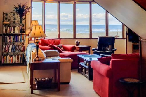 a living room with a couch and a table and windows at Expansive Views Family Oceanfront Beach Home in Westport