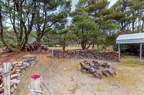 a garden with a pile of logs and a fence at Sand Castle Beach Home in Westport