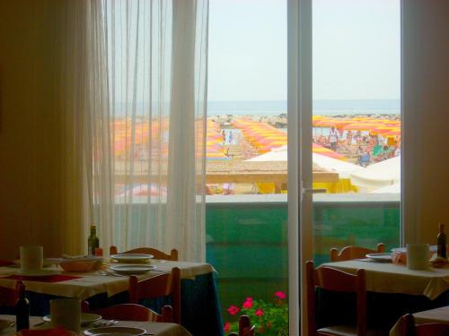 a dining room with a view of a large window at Hotel Cosmopolita in Rimini