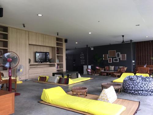 a room with yellow pillows and tables and chairs at S1hostel Bangkok in Bangkok