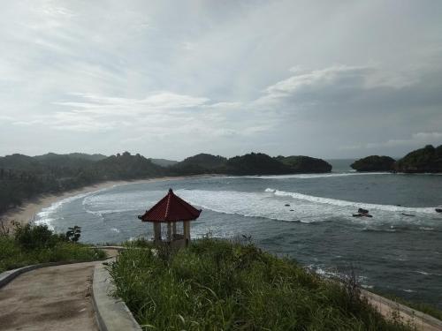 a beach with a gazebo next to the water at Harry's Ocean House Watukarung Homestay in Kalak