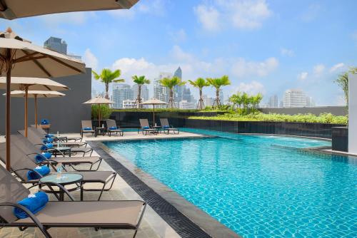 a swimming pool with chairs and umbrellas at Hotel Nikko Bangkok in Bangkok