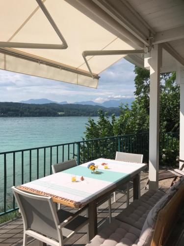 a table and chairs on a deck with a view of the water at Ferienwohnung Töschling Wörthersee in Techelsberg am Worthersee