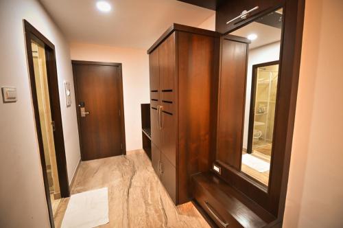 ein Badezimmer mit einem Holzschrank und einem Spiegel in der Unterkunft Chola Serviced Apartment in Tiruchchirāppalli