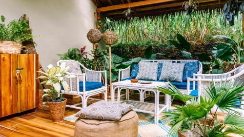 a patio with white chairs and a table and plants at Sampaguita Villas in El Nido