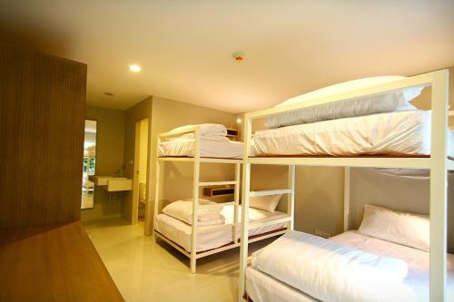 a room with two bunk beds with white sheets at CHERN Bangkok in Bangkok
