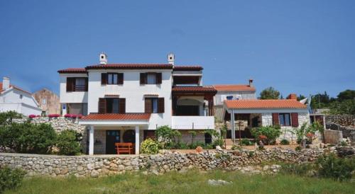 a large white house with a stone wall at Apartman Slavko in Zverinac