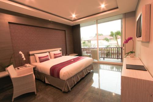 a bedroom with a bed and a balcony at Transera Kamini Legian Hotel in Legian