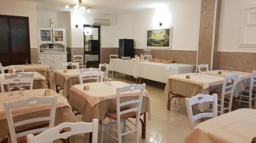 uma sala de jantar com mesas e cadeiras brancas em Albergo Primavera em Porto Cesareo