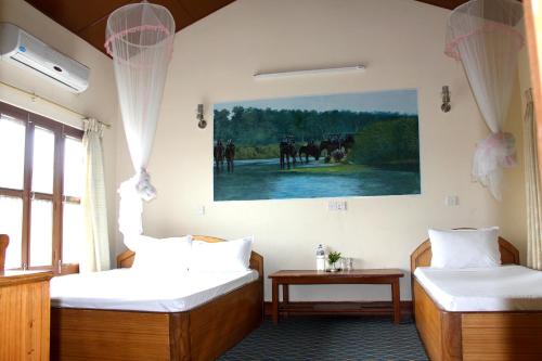 two beds in a room with a painting on the wall at Rhino Land Jungle Lodge in Sauraha