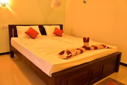 a bedroom with a bed with white sheets and orange pillows at La Casa Safari Resort in Udawalawe