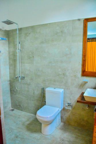 a bathroom with a toilet and a shower and a sink at Amuththa Resort in Anuradhapura