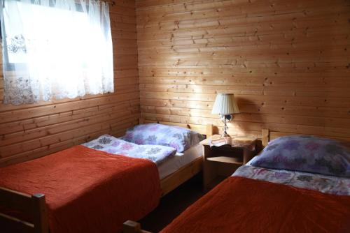 two beds in a wooden room with a window at Nestor Domki in Mrzeżyno