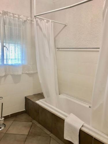 a bathroom with a bath tub with a shower curtain at Summerplace Holiday Home in Hazyview