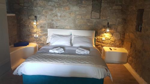 a bedroom with a bed and a stone wall at Amallini Suites Mykonos in Super Paradise Beach