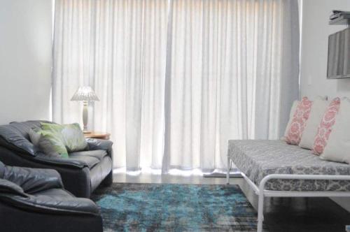 a living room with a couch and a window with curtains at 21 ON BAKOOND in Yzerfontein