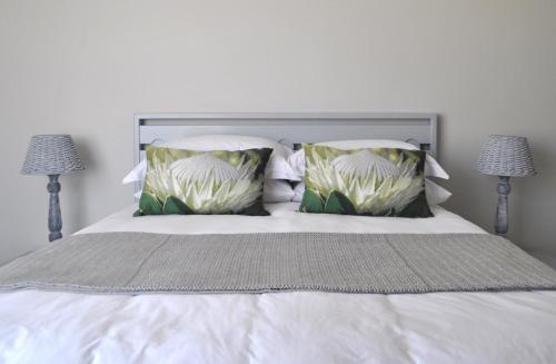 a white bed with two pillows and two lamps at 21 ON BAKOOND in Yzerfontein