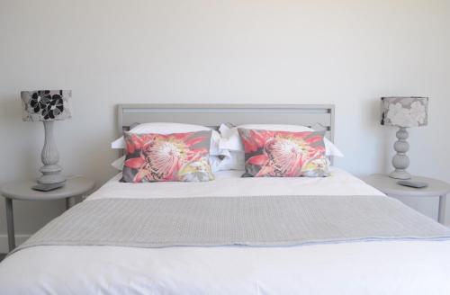a bedroom with a bed with two lamps and two pillows at 21 ON BAKOOND in Yzerfontein