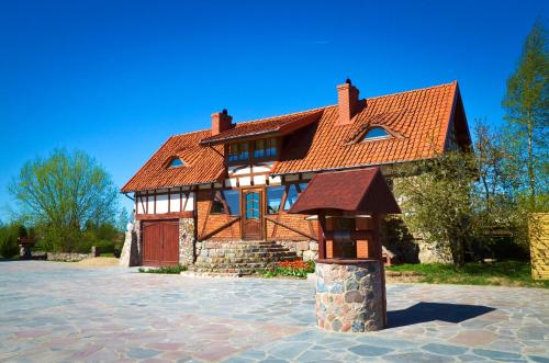 a house with a red roof and a stone pillar at Dom na wodzie Mazury in Dźwierzuty