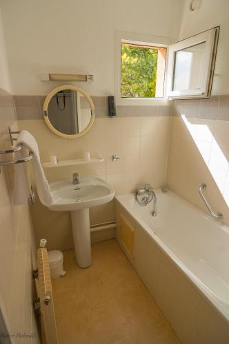une salle de bain avec un lavabo, une baignoire et un miroir dans l'établissement Association Villa Saint Camille, à Théoule-sur-Mer