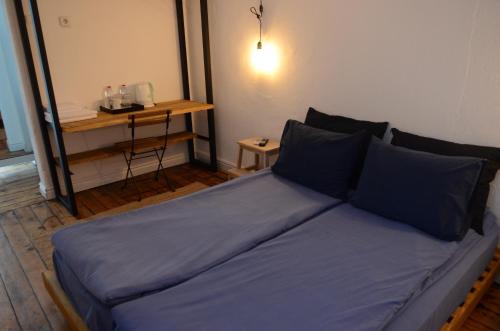 a bed with blue sheets in a room with a table at Generaator Sofia in Sofia