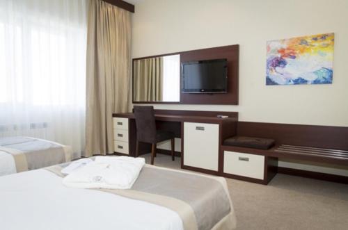 a hotel room with two beds and a desk and a television at Black Mount Hotel in Baku