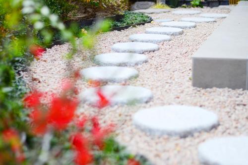 a pathway with stepping stones in a garden with flowers at BEPPU HOSTEL U&T in Beppu