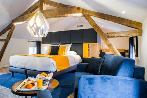 - une chambre avec un lit king-size et des chaises bleues dans l'établissement Logis Hôtel Le Tilia, à Joux